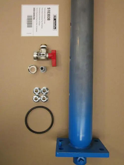 Remeha Rücklaufwasserverteilrohr mit Montageplatten, Ventil, Dichtungen und verschiedenen Edelstahlmuttern auf Kartonuntergrund.